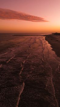 Beautiful sunset scene with calm waves and a pastel sky on a serene beach.