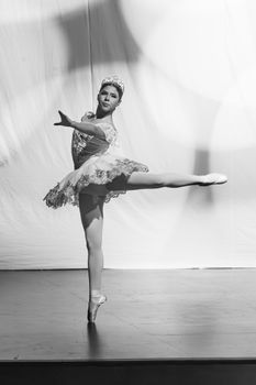 Elegant ballerina performing a stunning arabesque during a black and white photoshoot.