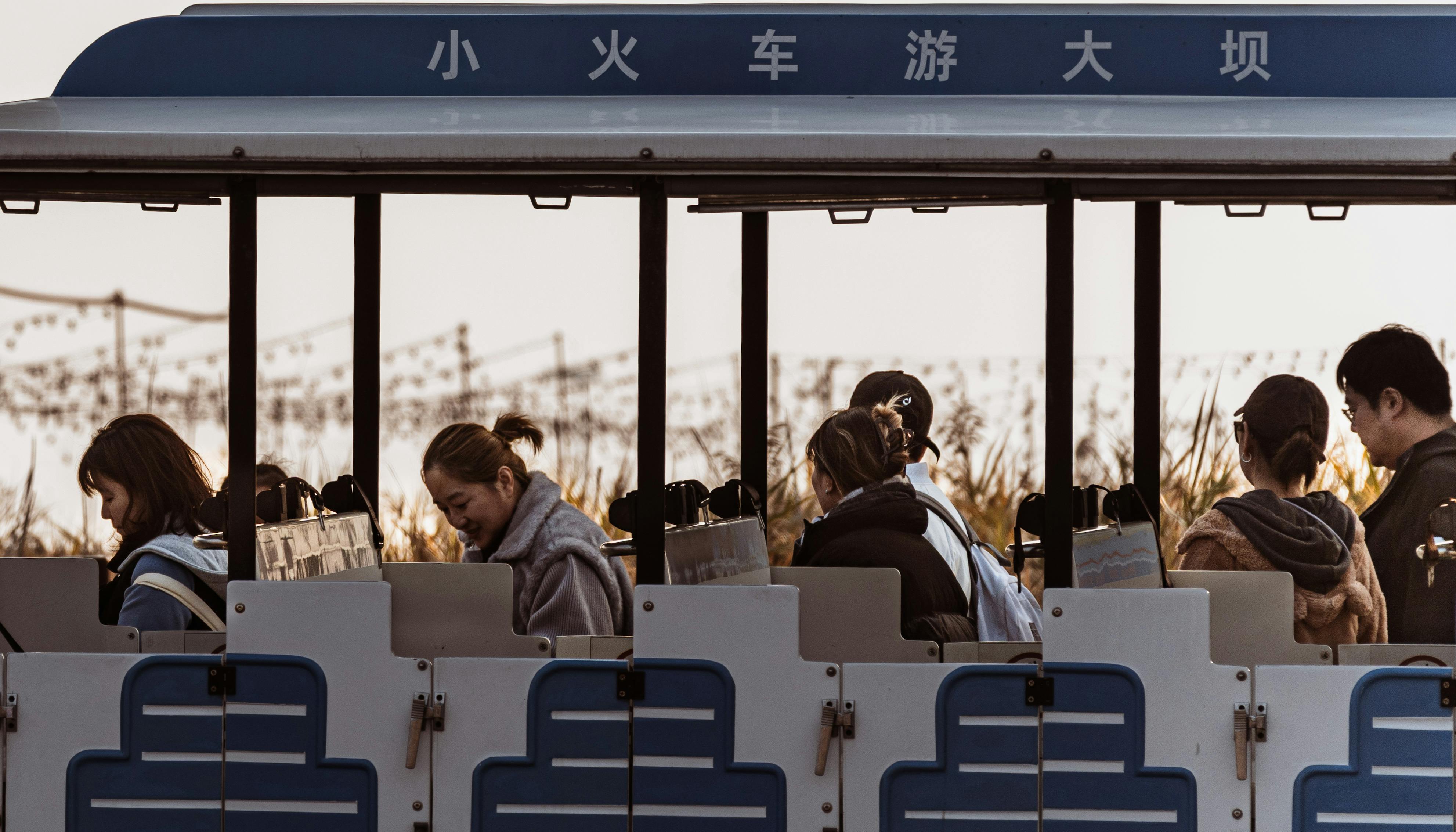Group of passengers enjoying a scenic tram ride through beautiful landscape at sunset.