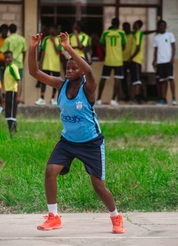 Young athlete in blue jersey playing basketball energetically on outdoor court.