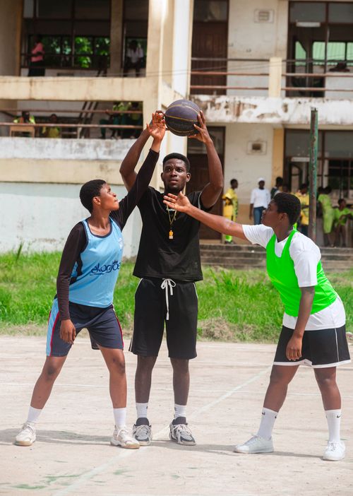 Free Teenagers engage in a competitive basketball game outdoors, showcasing teamwork and athleticism. Stock Photo
