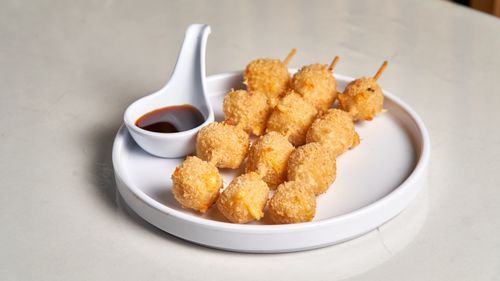 Free Delicious crispy fried snacks on skewers with soy sauce dip on a white plate. Stock Photo