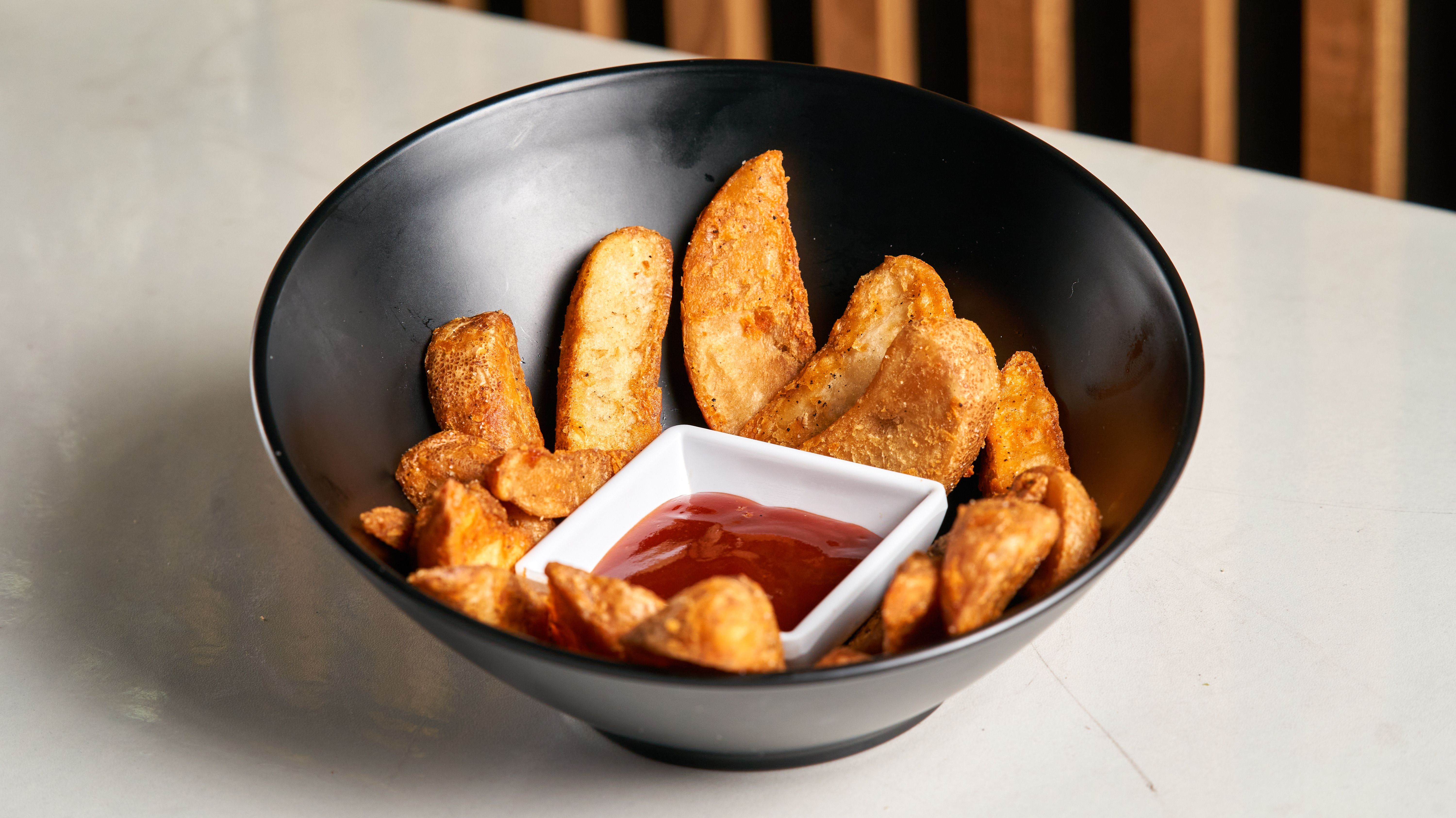 crispy avocado wedges on a plate with dipping sauce, golden and textured