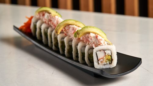 Free Delicious sushi roll with avocado and crab, beautifully presented on a black plate. Stock Photo