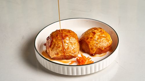 Free Baked pastries drizzled with honey, served on a white plate with carrot garnish. Stock Photo