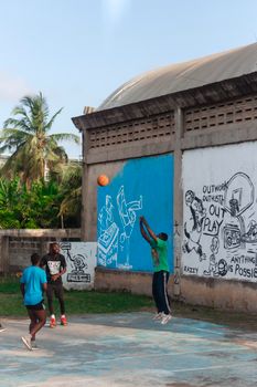 Group of teenagers playing basketball outdoors against a vibrant mural backdrop. Energetic and dynamic scene.