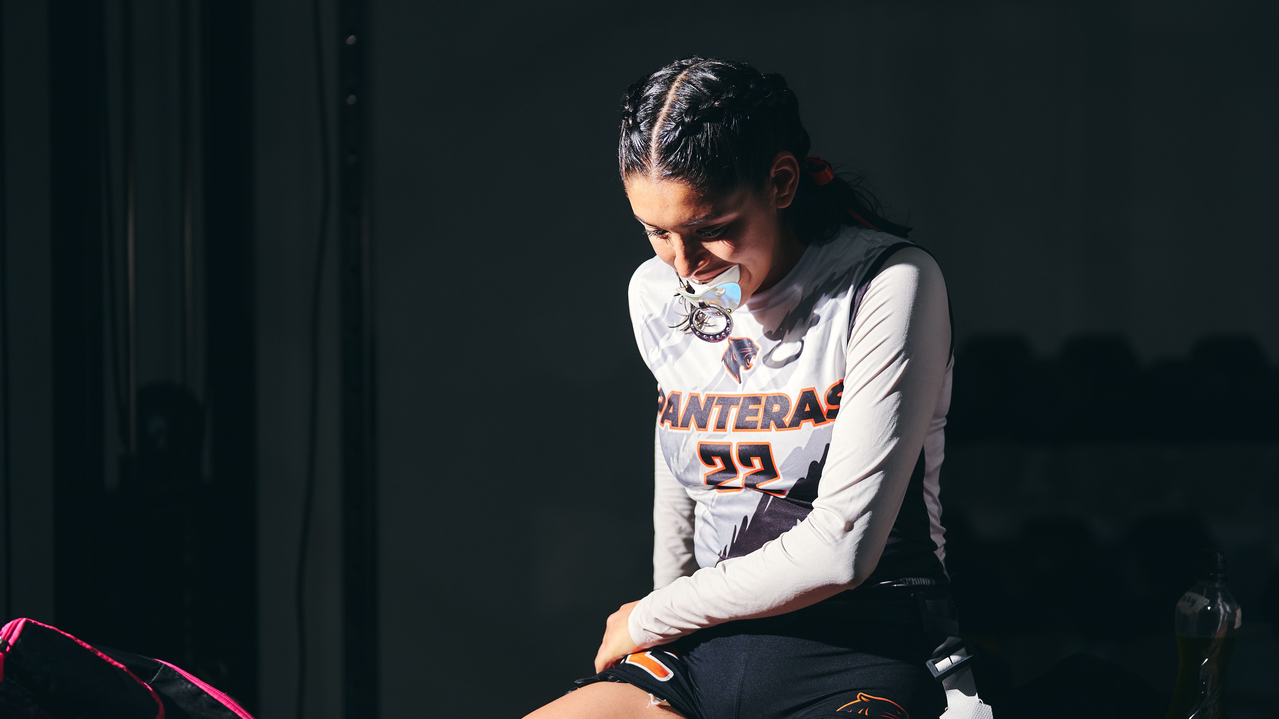 Focused female athlete wearing a mouthguard and sitting on a bench, preparing for sports activity.