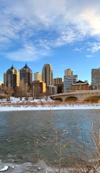 Captured on a winter day, Calgary's skyline reflected in the Bow River with snow-covered banks.