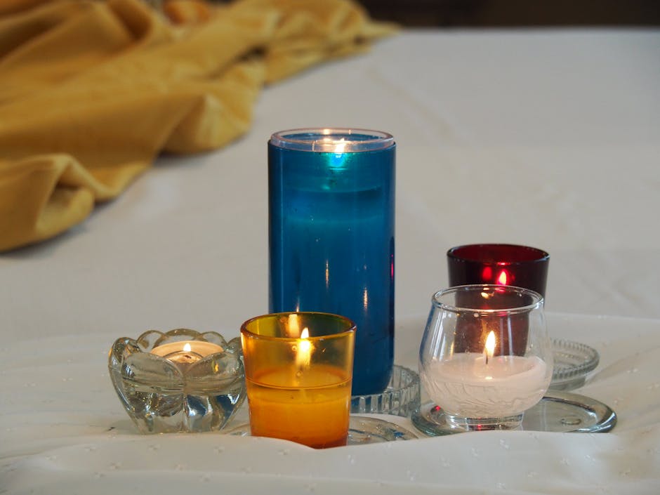 Five colorful candles lit on white linen, creating a warm and serene atmosphere.