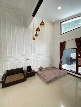 A minimalist bedroom featuring a huge window, pendants, and floor seating for a contemporary look.