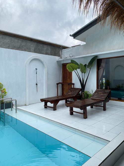 Free A serene indoor poolside area with wooden loungers, perfect for relaxation and leisure in a minimalist setting. Stock Photo
