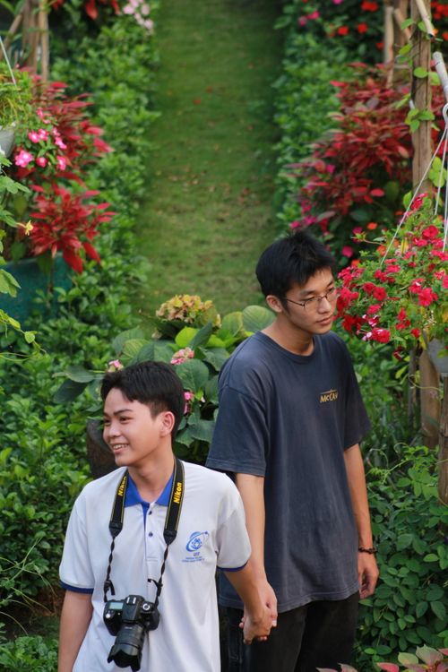 Free Two young men walking through a colorful garden, capturing moments. Stock Photo