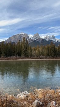 Breathtaking view of the Three Sisters mountains over a serene river, perfect for travel and nature enthusiasts.
