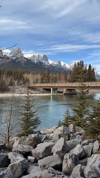Breathtaking view of river, bridge, and snow-capped mountains under a clear blue sky.