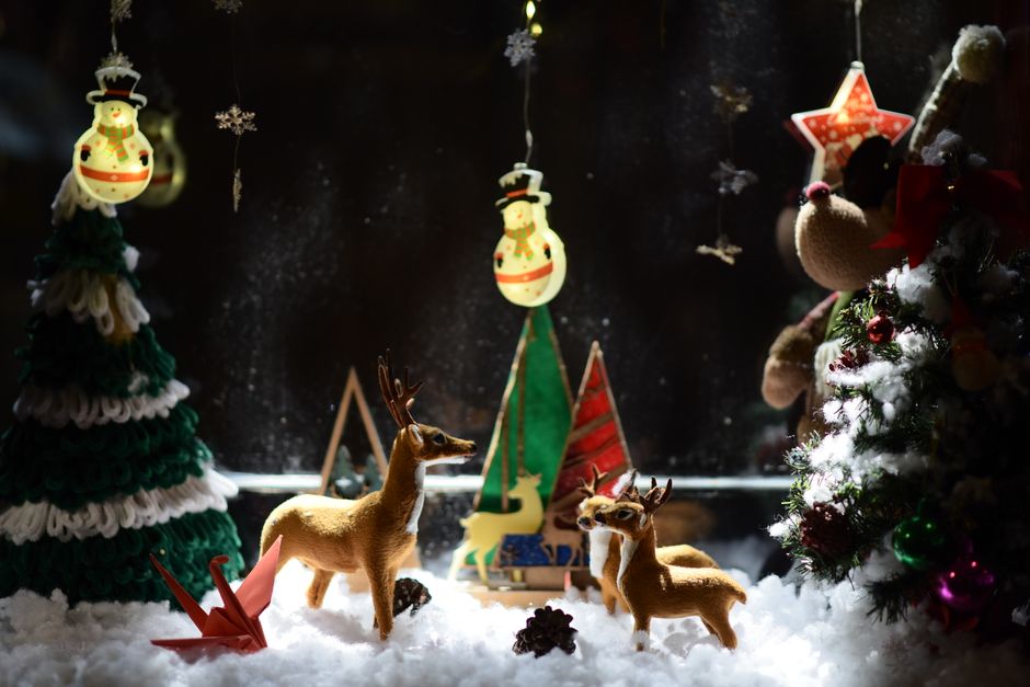 Captivating Christmas scene with reindeer amid snowflakes and decorated trees.