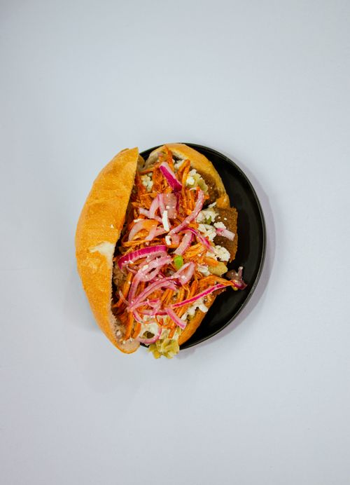 Free Vibrant vegan sandwich filled with fresh veggies on a black plate, perfect for healthy eating. Stock Photo