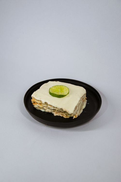 Free Slice of key lime cake with topping on a black plate, isolated against a white background. Stock Photo
