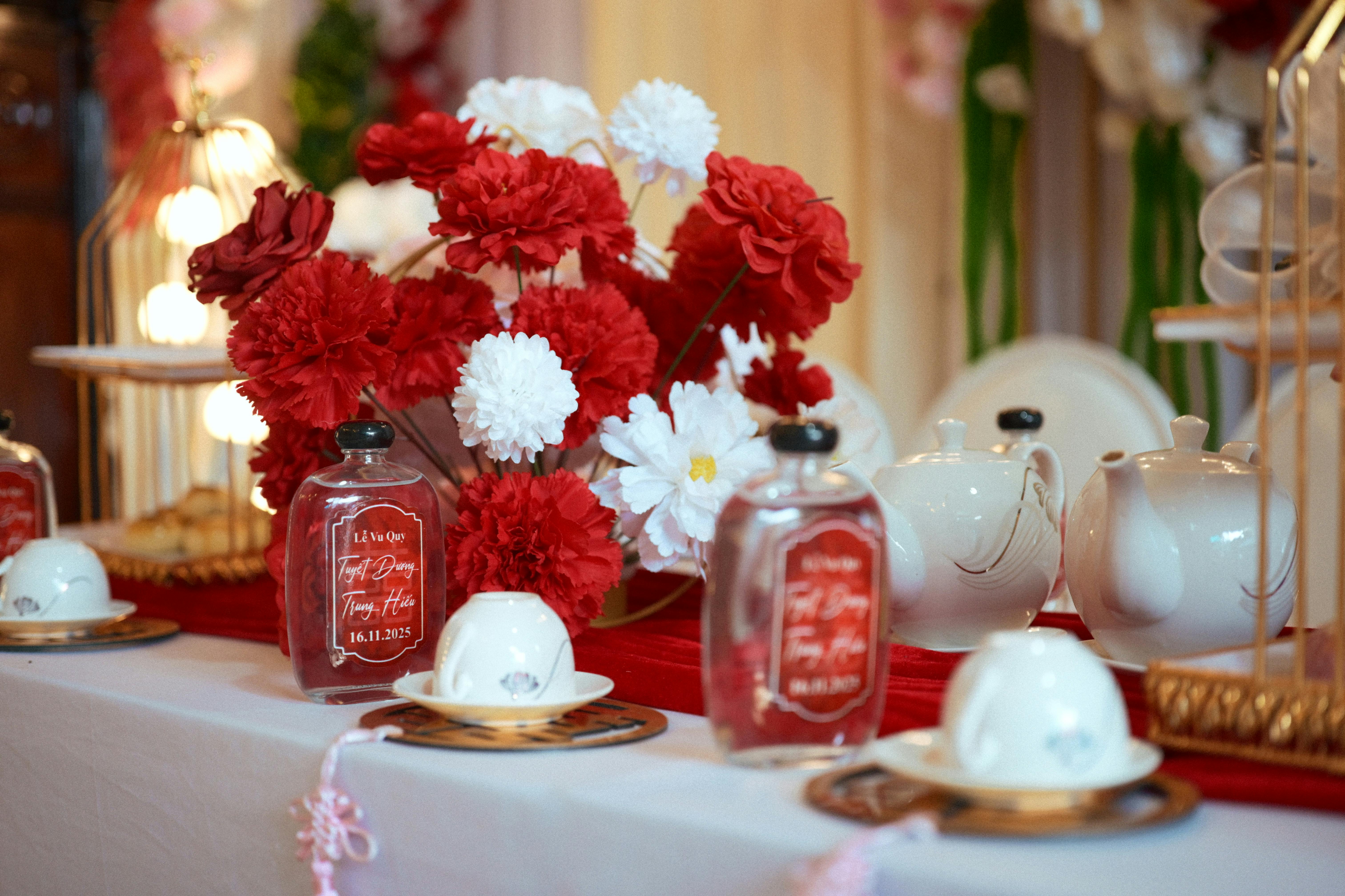trà sơn mật hồng sâm - Bộ ấm trà cưới thanh lịch với hoa đỏ và trắng, hoàn hảo cho những buổi lễ lãng mạn.