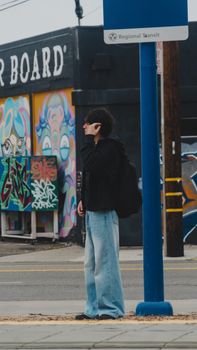 A person on a city street near vibrant graffiti art, evoking an urban lifestyle.