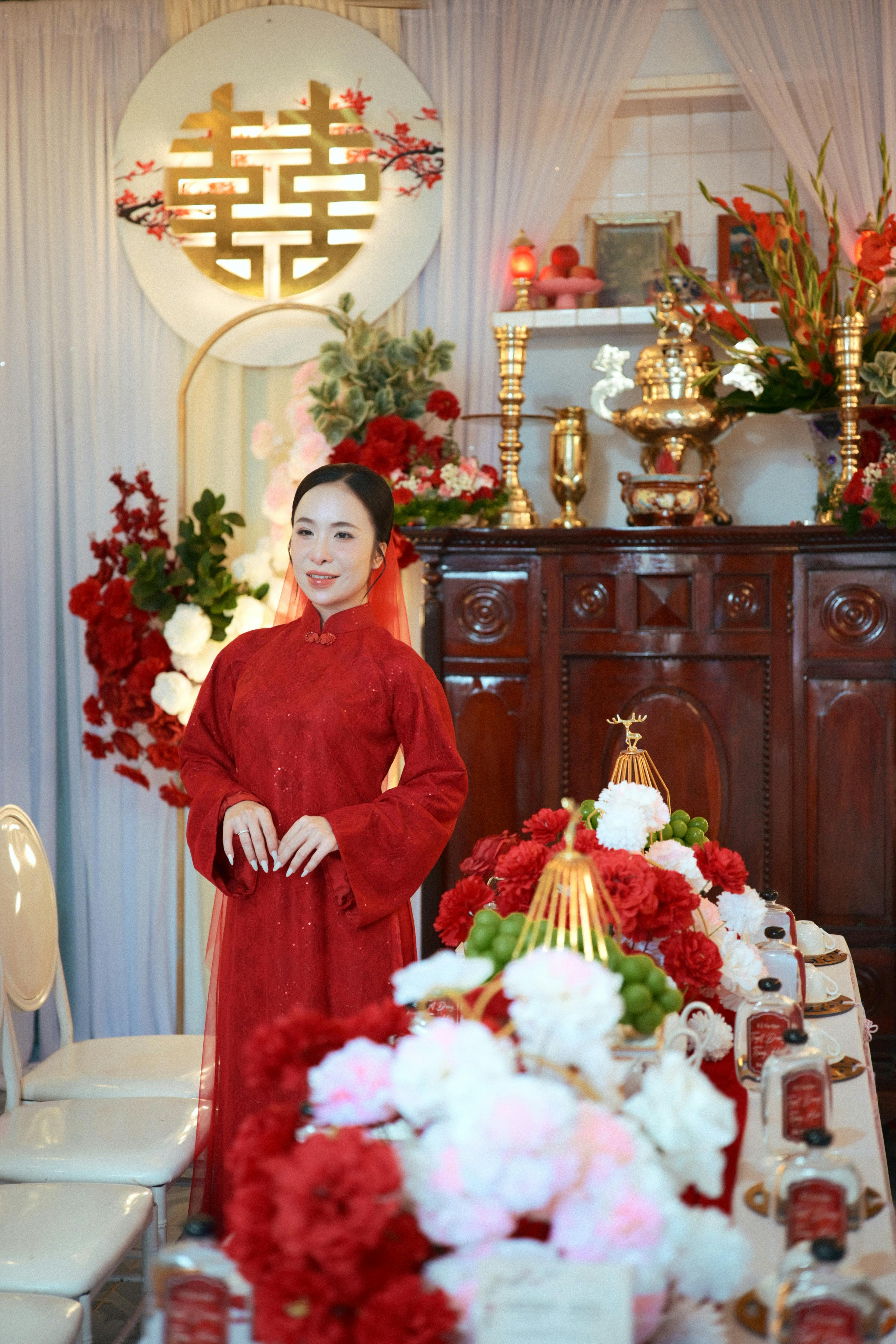 A traditional wedding setup with vibrant red decorations and attire in an indoor setting.