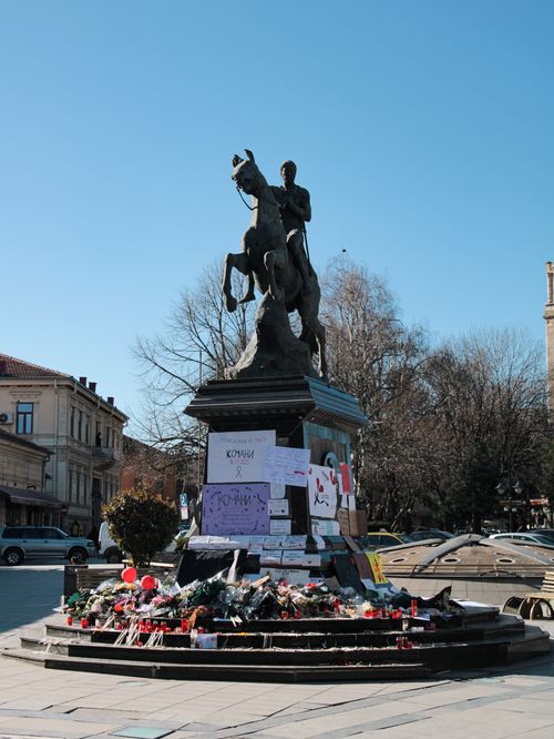 Free Equestrian statue surrounded by tributes in a city square, captured on a clear day. Stock Photo