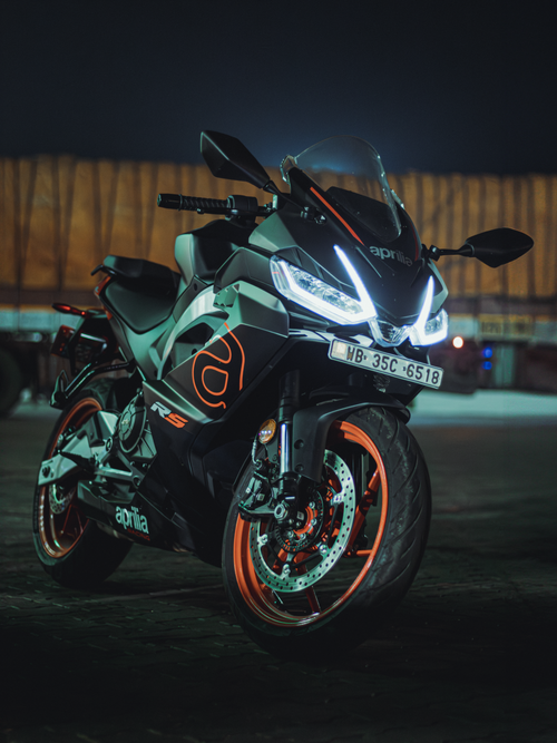 Free High-performance Aprilia motorcycle with glowing LED lights set against a dramatic night backdrop. Stock Photo