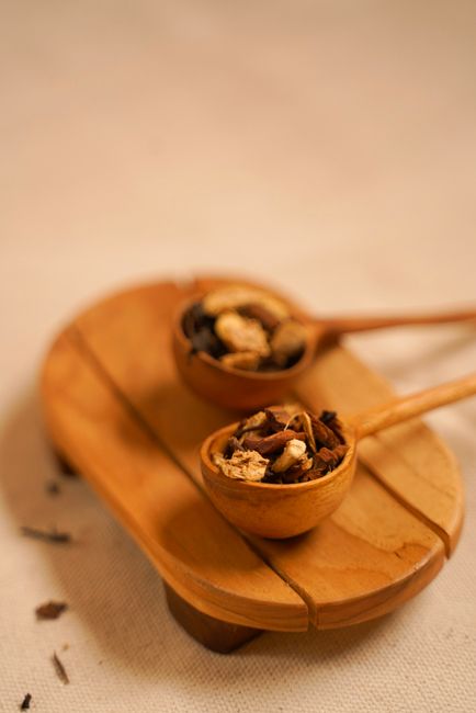 Fotomural Imagen de tonos cálidos de mezclas de té rústico en cucharas de madera sobre una bandeja para servir, creando un ambiente acogedor.