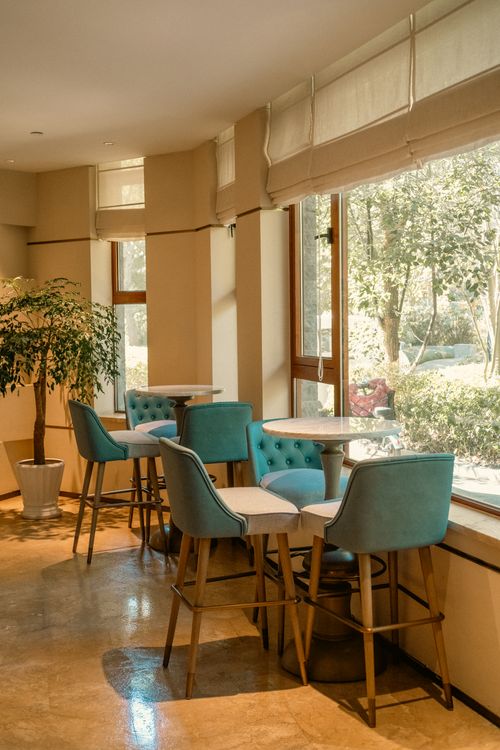 Free Cozy hotel lounge with blue chairs and natural light, offering a serene and inviting atmosphere. Stock Photo