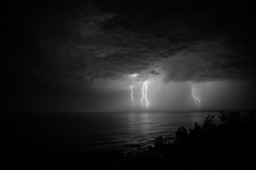 Free Black and white shot of lightning striking over the ocean at Culburra Beach. Stock Photo