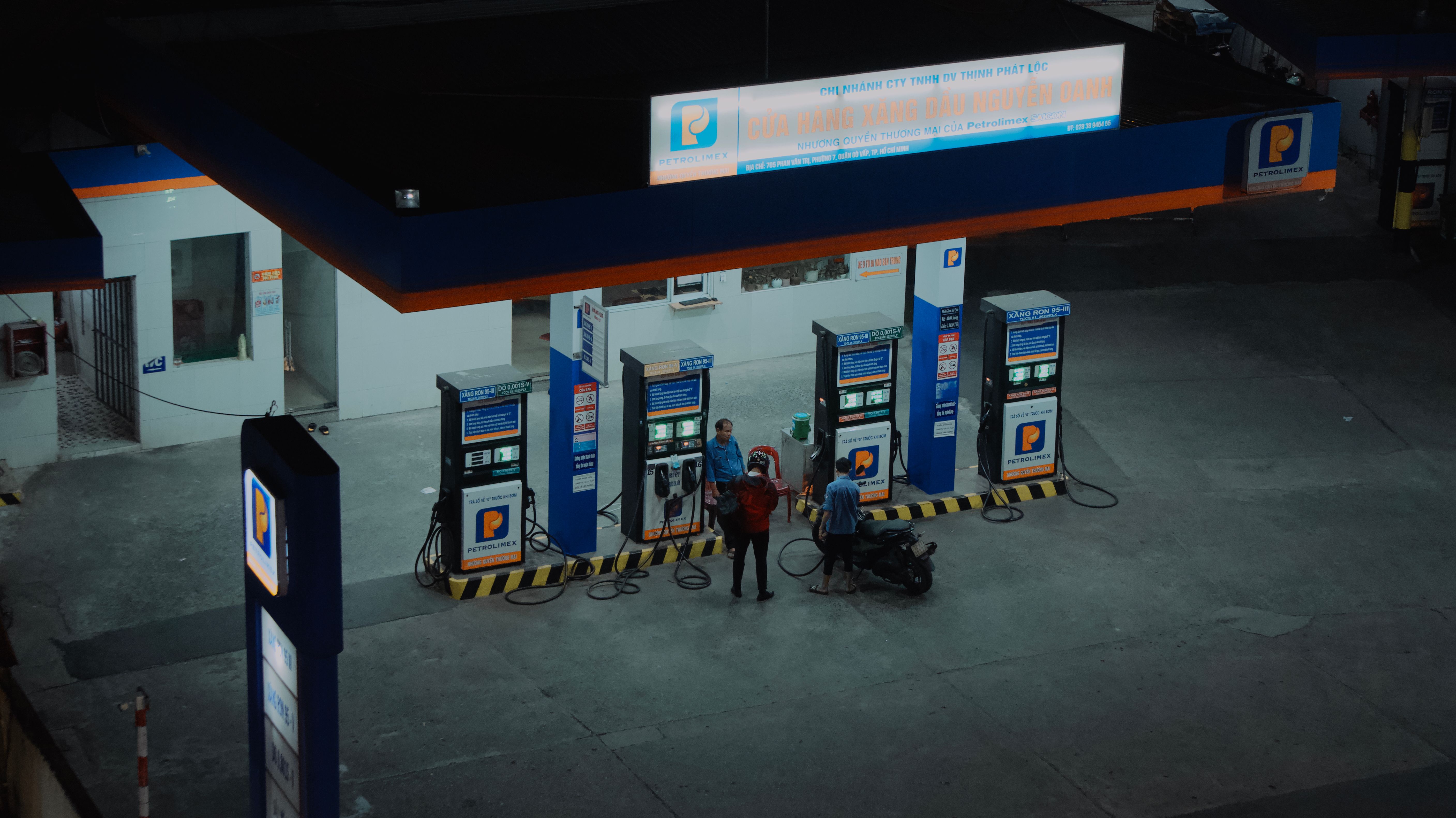Aerial view of a gas station with people fueling motorcycles at night.