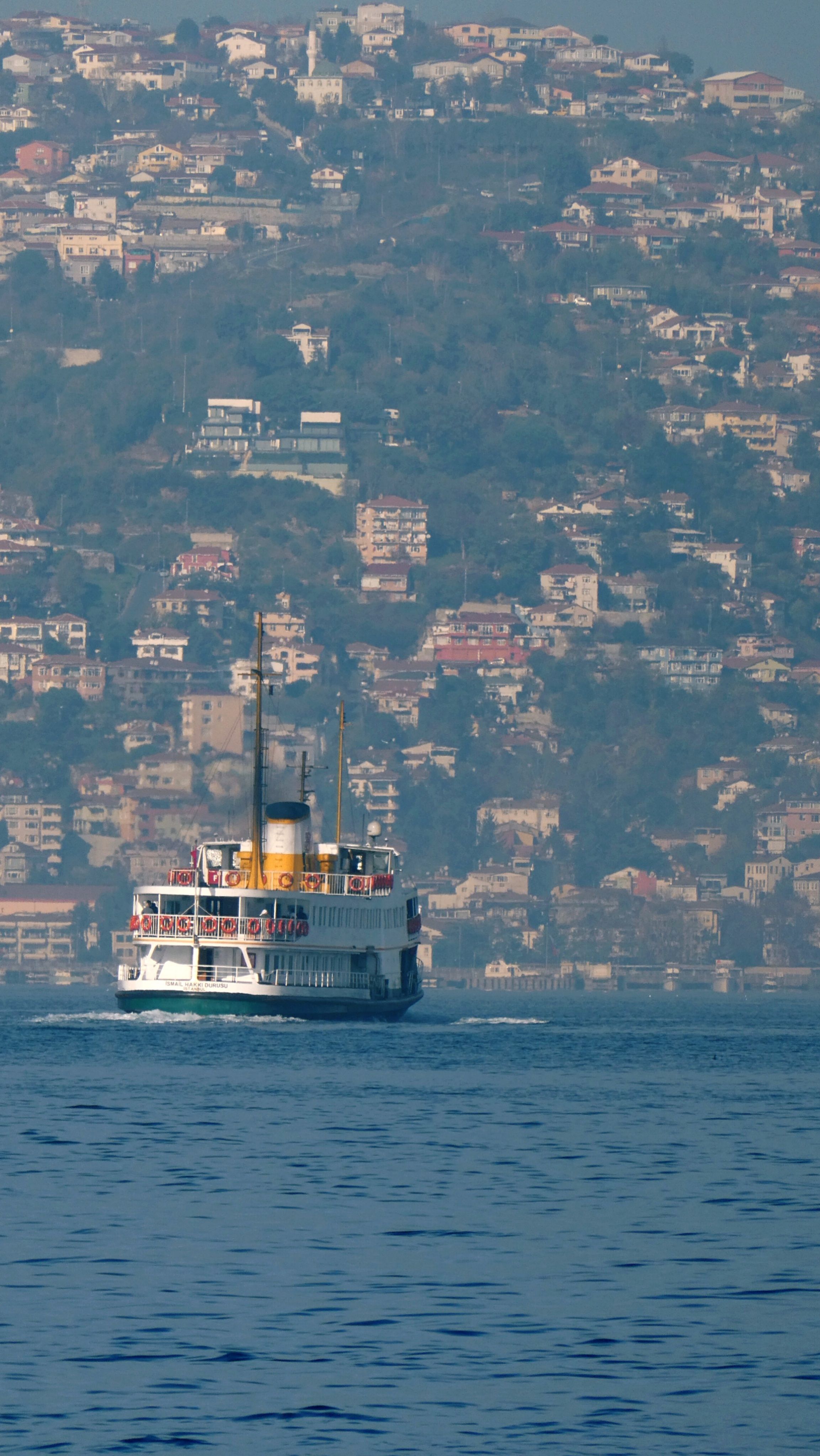 A traditional ferry sails on the Bosphorus, set against Istanbul's scenic hills.