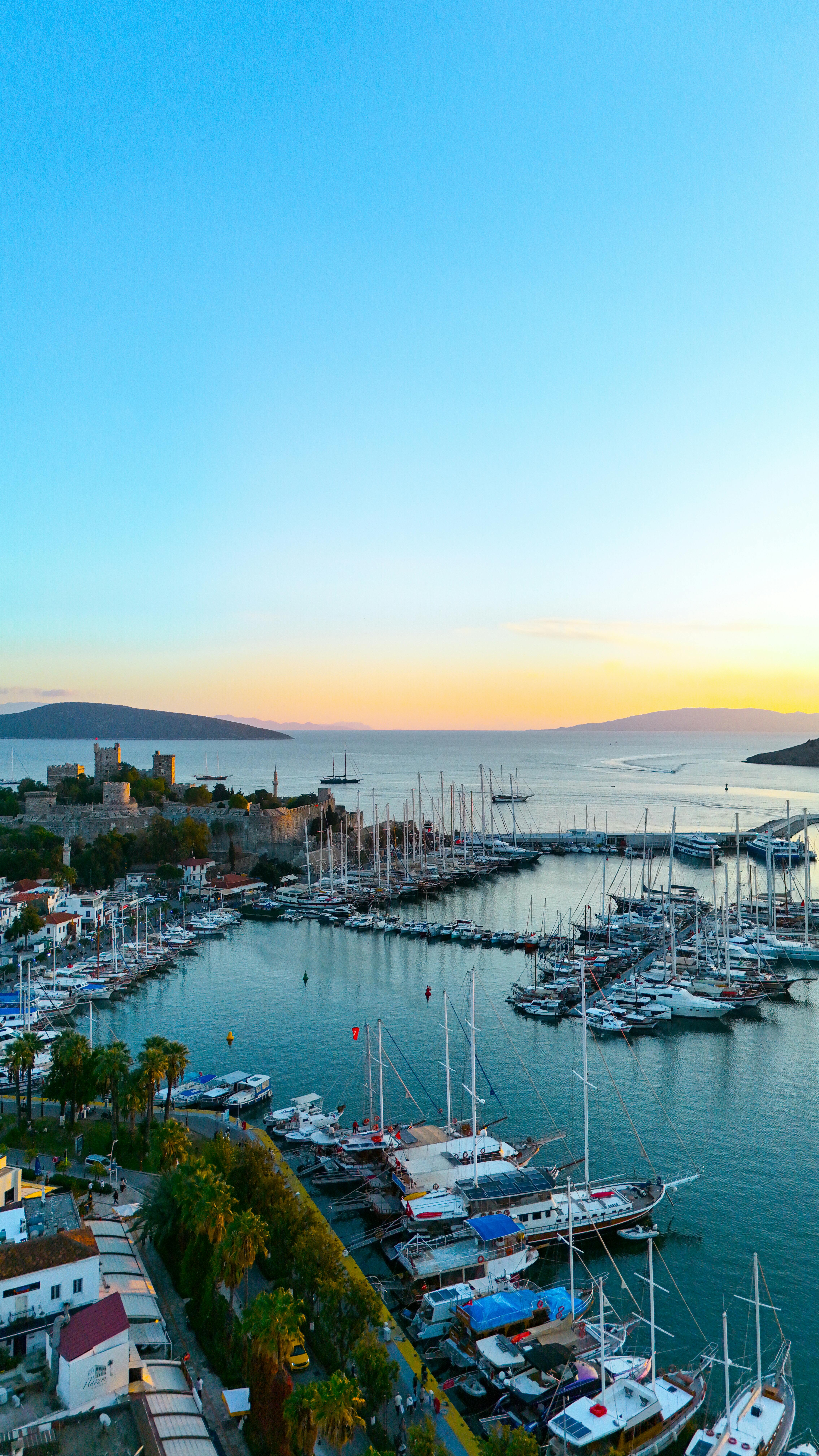 grátis Vista deslumbrante do pôr do sol sobre a marina de Bodrum, com iates e o castelo na costa da Turquia. Foto profissional