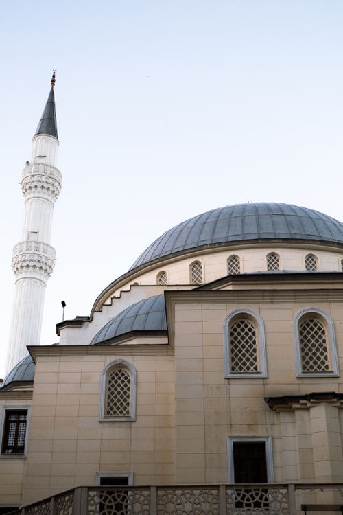 Free Beautiful view of an Ottoman-style mosque with a domed roof and minaret under a clear sky. Stock Photo