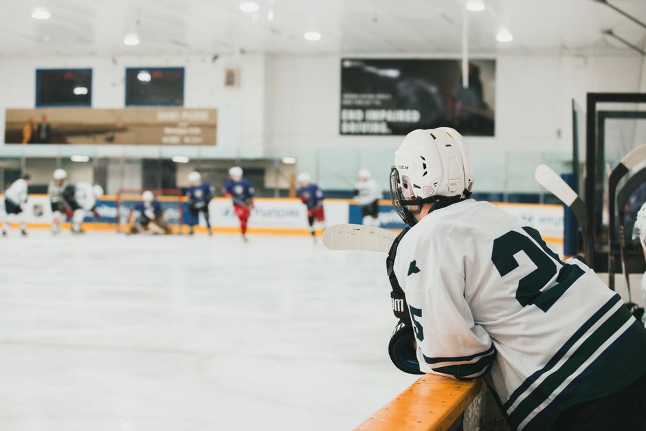 How to Evaluate Any Sportsbook Bonus in Canada (2026 Guide) Adult ice hockey player in white jersey observing match from bench indoors.