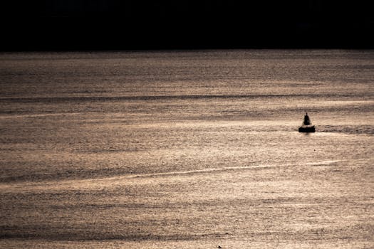 A solitary buoy floats on a calm water surface during sunset, creating a tranquil scene.
