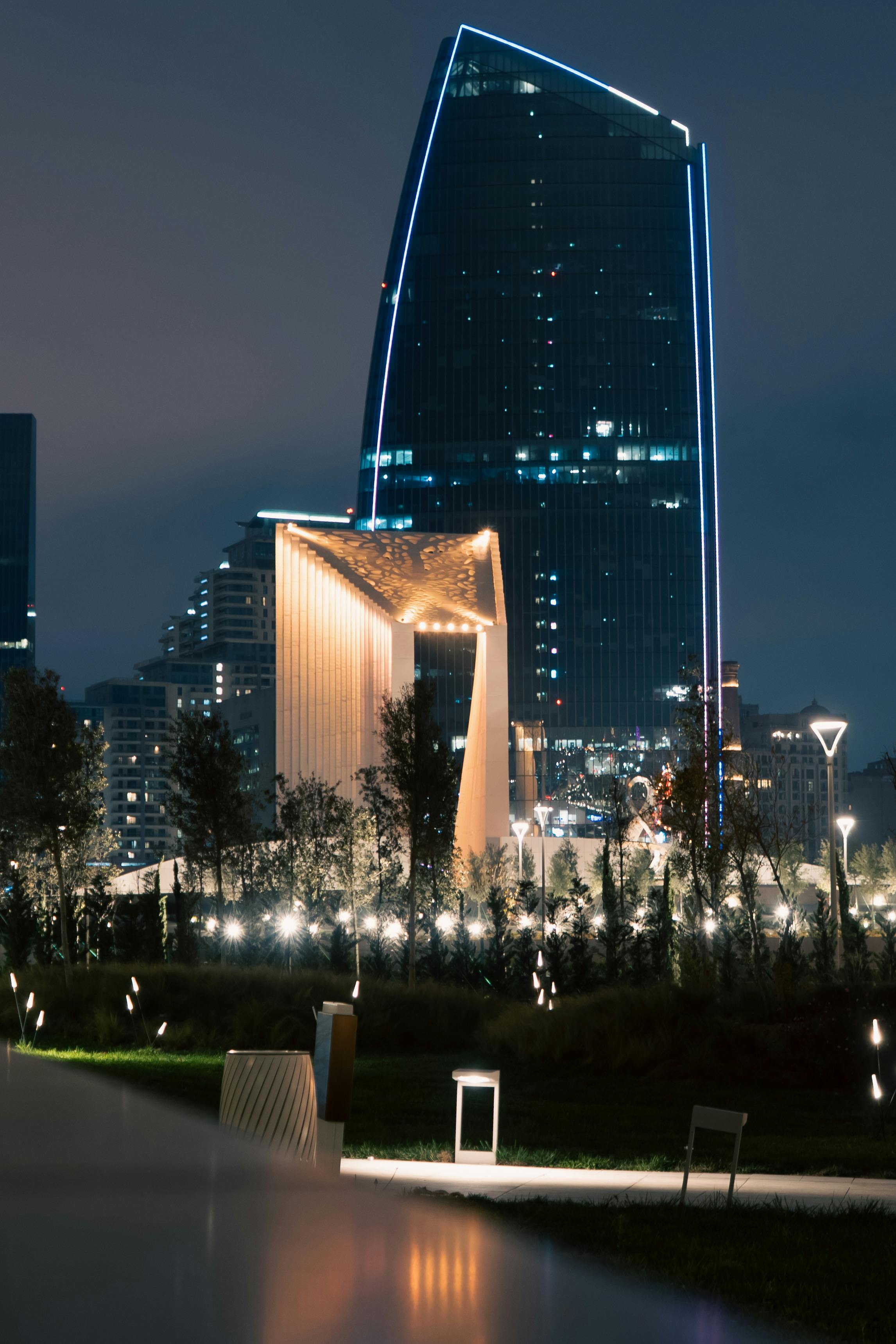 Nighttime view of a futuristic cityscape featuring a uniquely designed illuminated skyscraper.