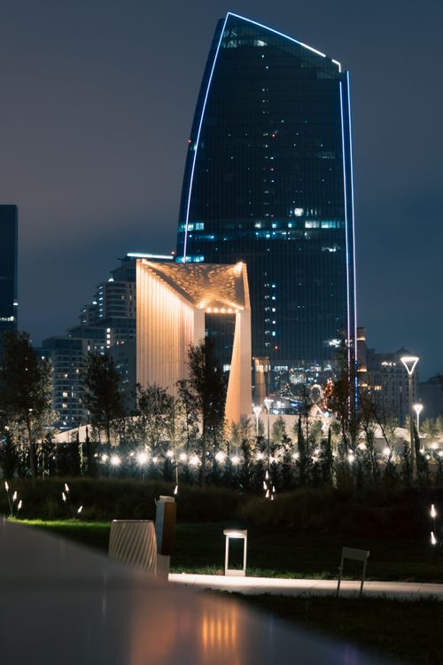 Free Nighttime view of a futuristic cityscape featuring a uniquely designed illuminated skyscraper. Stock Photo