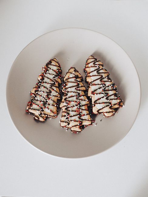 Delicious holiday cookies shaped as trees with icing and sprinkles on a plate.