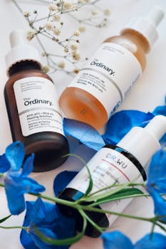 Aesthetic display of skincare serums with vibrant blue flowers on a light background.