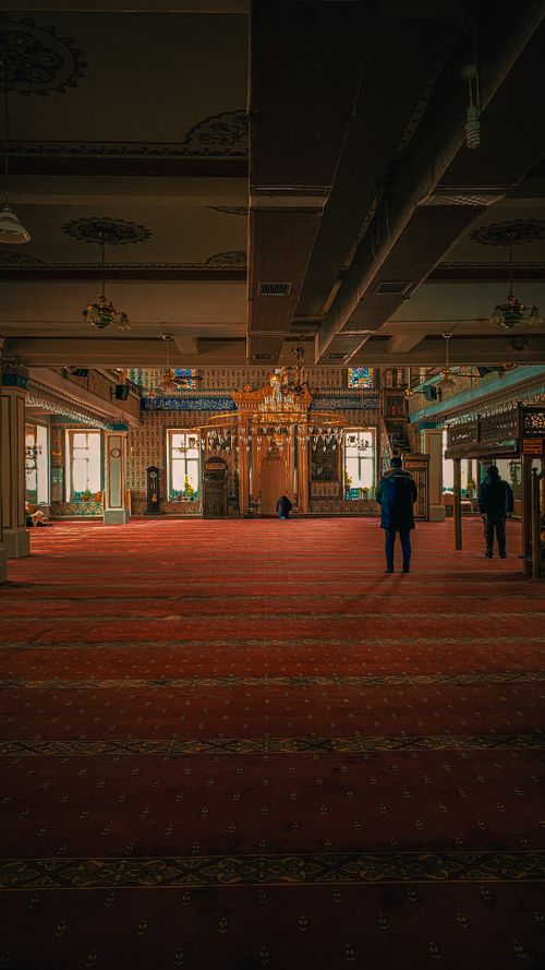 Free Intricately decorated mosque interior with vibrant red carpet and chandeliers. Stock Photo