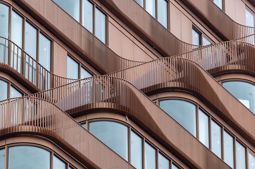 Free Close-up of a modern building facade featuring stylish curved balconies and large windows. Stock Photo