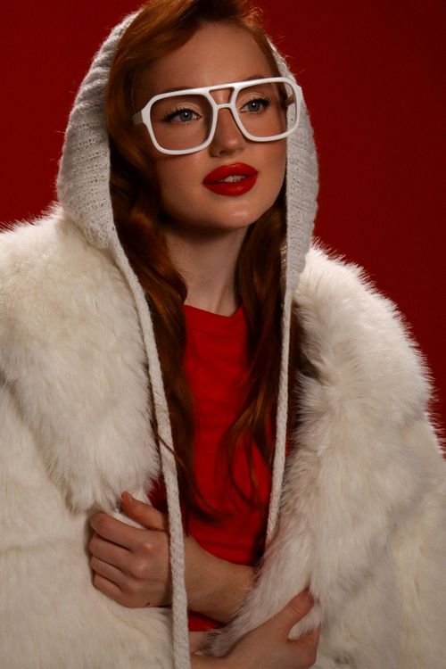 Free Fashionable woman in glasses wearing white fur coat against red background. Stock Photo