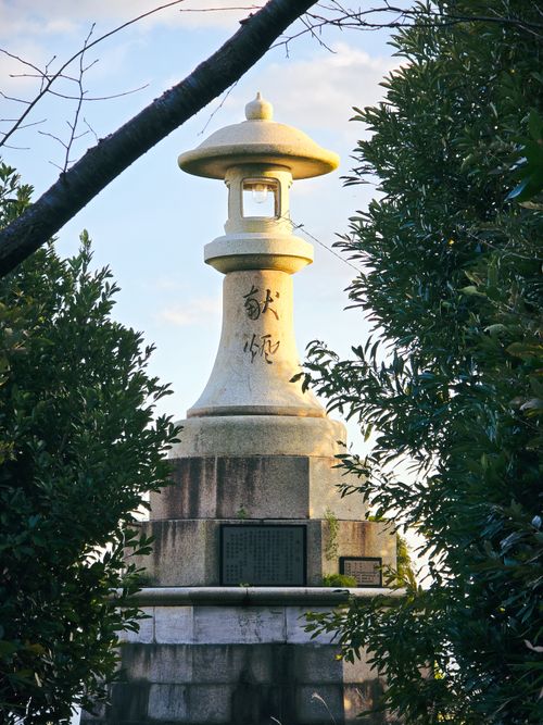 Free Stone lantern surrounded by greenery under clear sky, showcasing Japanese culture. Stock Photo