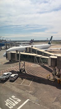 Cathay Pacific airplane parked at airport terminal gate under clear skies.