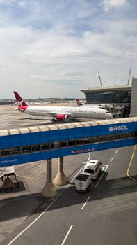 Virgin Atlantic airplane parked at a busy airport terminal with clear skies.
