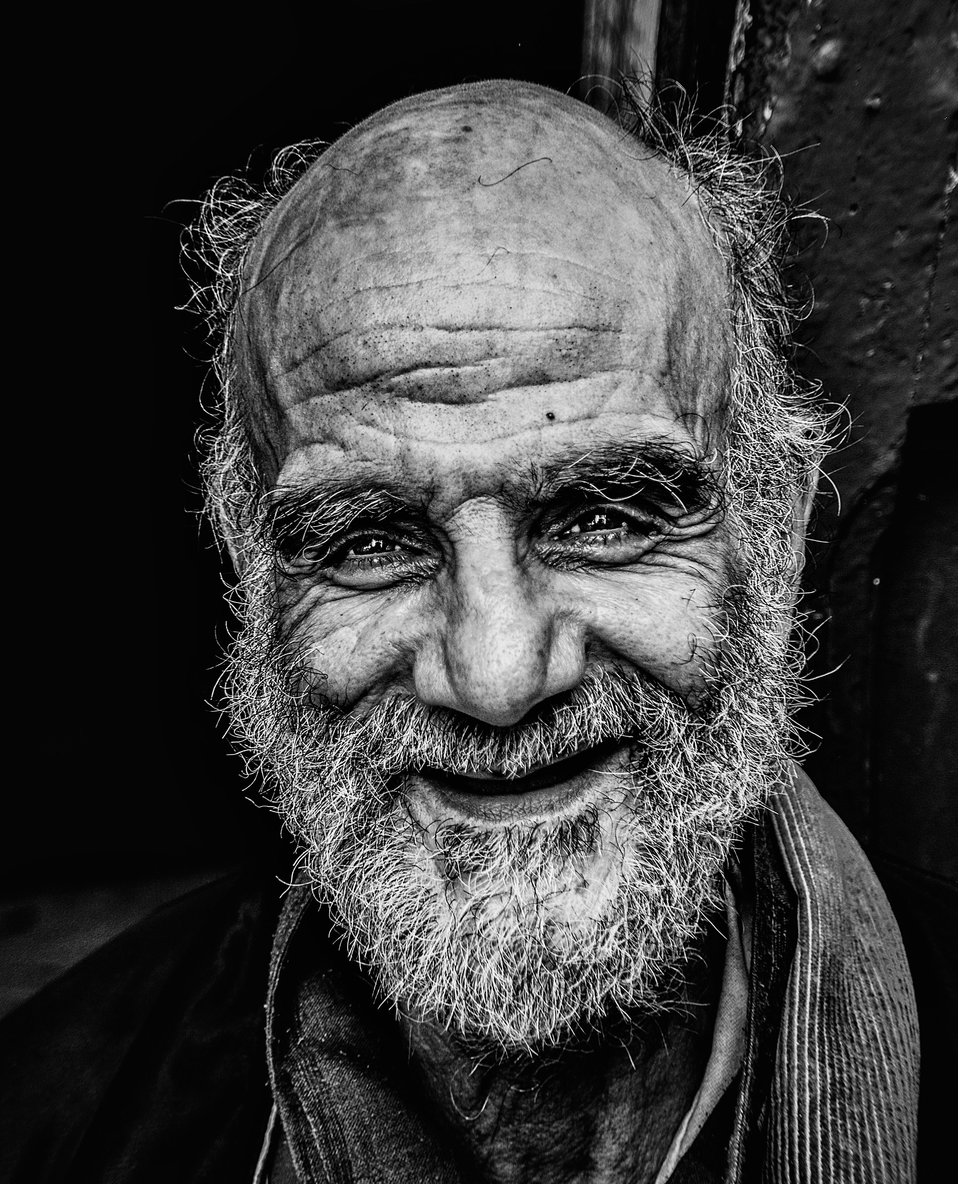 A captivating black and white portrait showcasing the expressive face of an elderly man with a gentle smile.