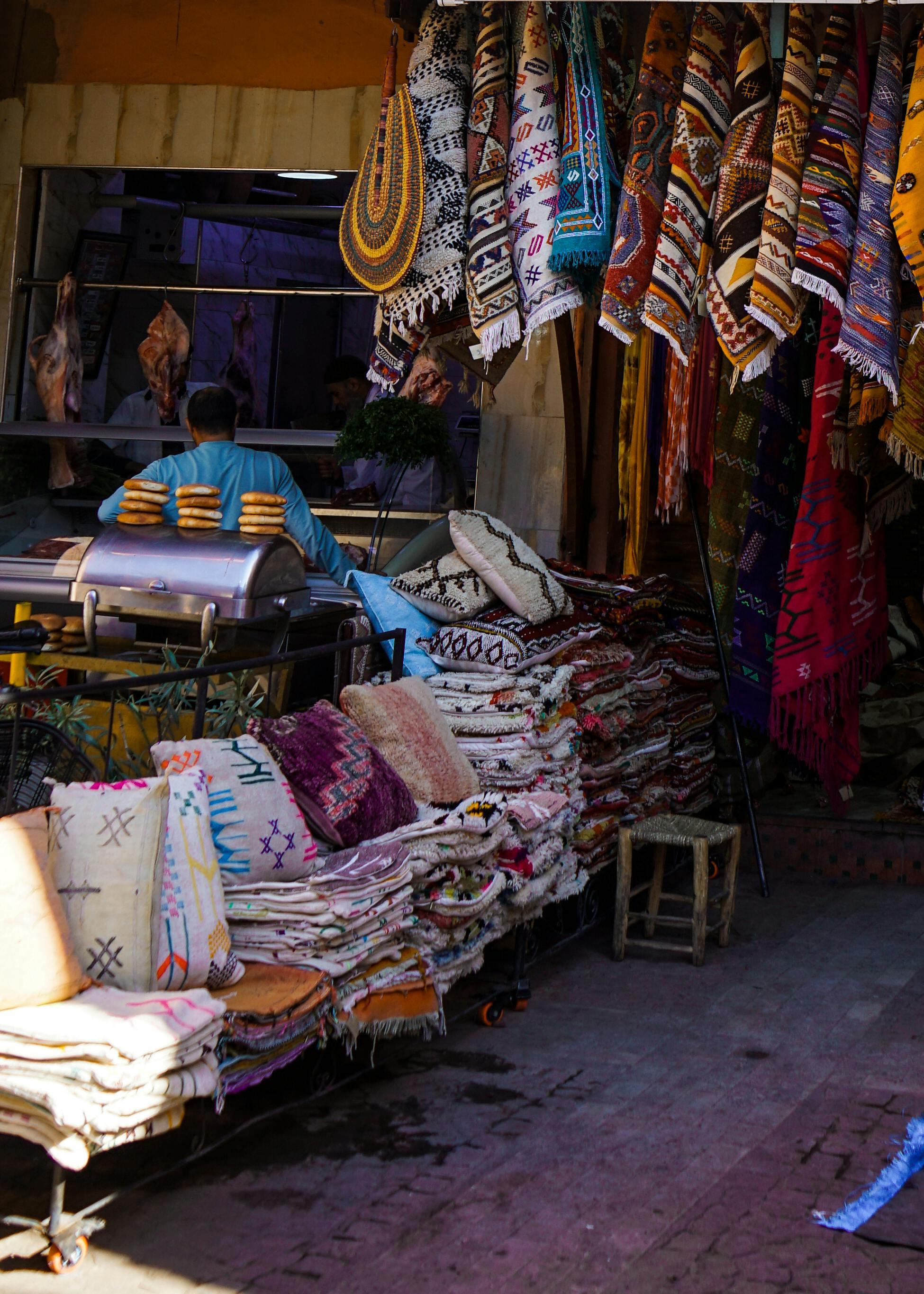 Colorful textiles and carpets hanging in a bustling Marrakech market, showcasing Moroccan culture.