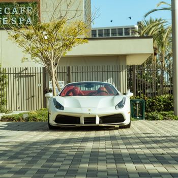White sports car parked outdoors in a city setting with modern architecture.
