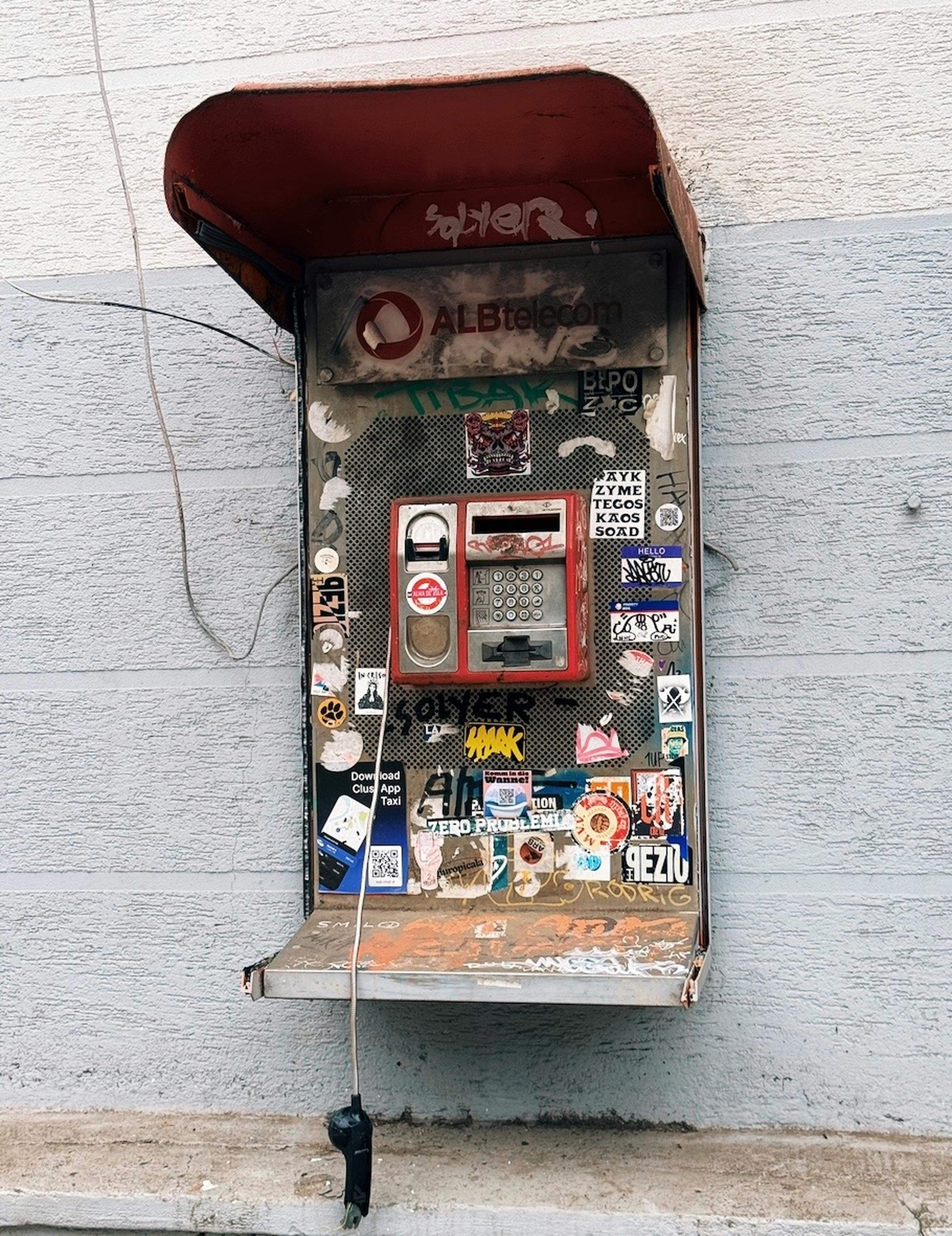 Gratis Una cabina telefonica pubblica d'epoca decorata con graffiti urbani in un ambiente esterno. Foto a disposizione