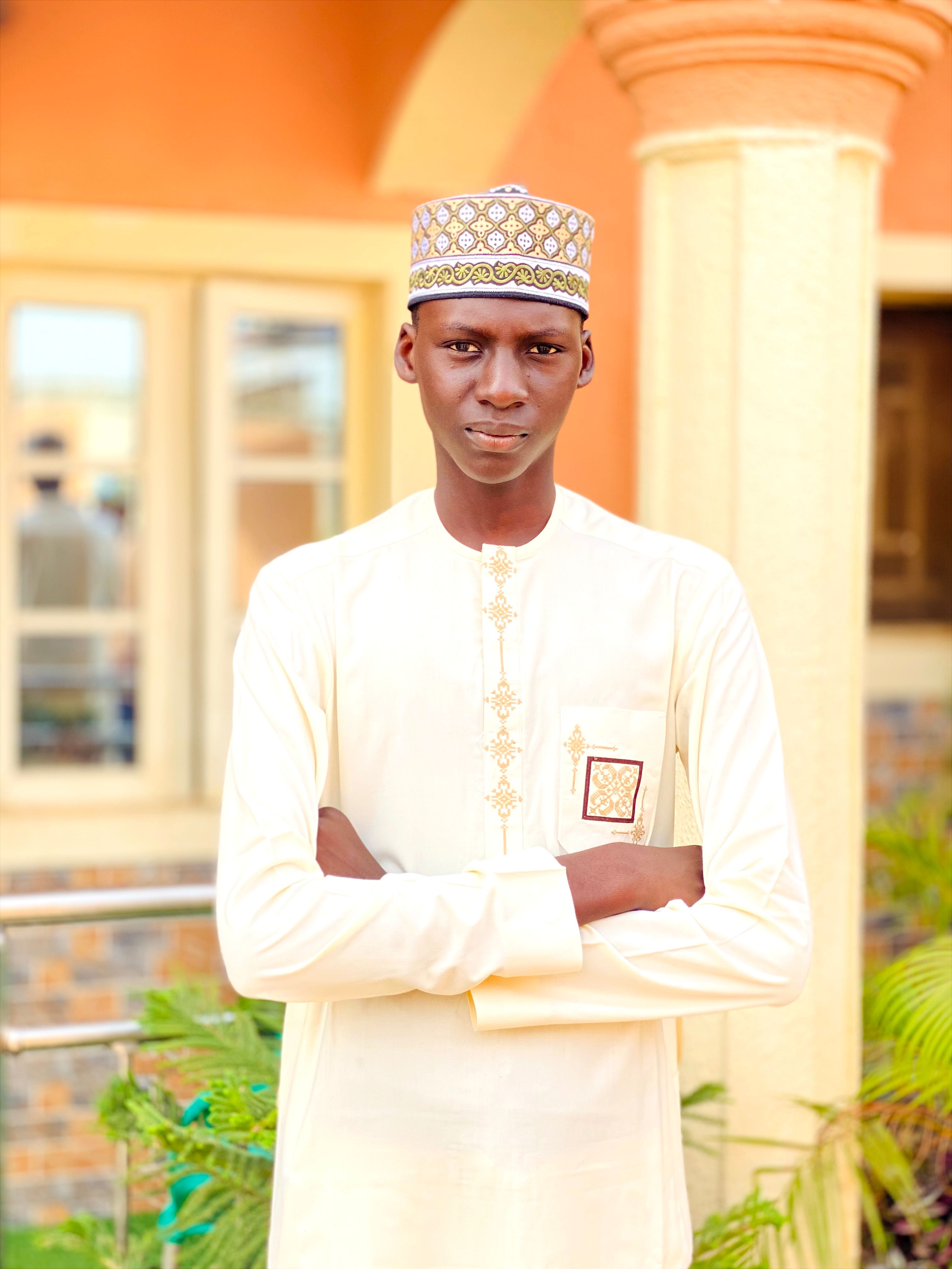 A young man wearing traditional attire stands confidently outdoors, showcasing cultural style.